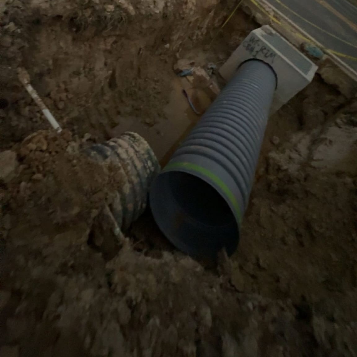 Excavator digging drainage ditch and setting culvert pipe