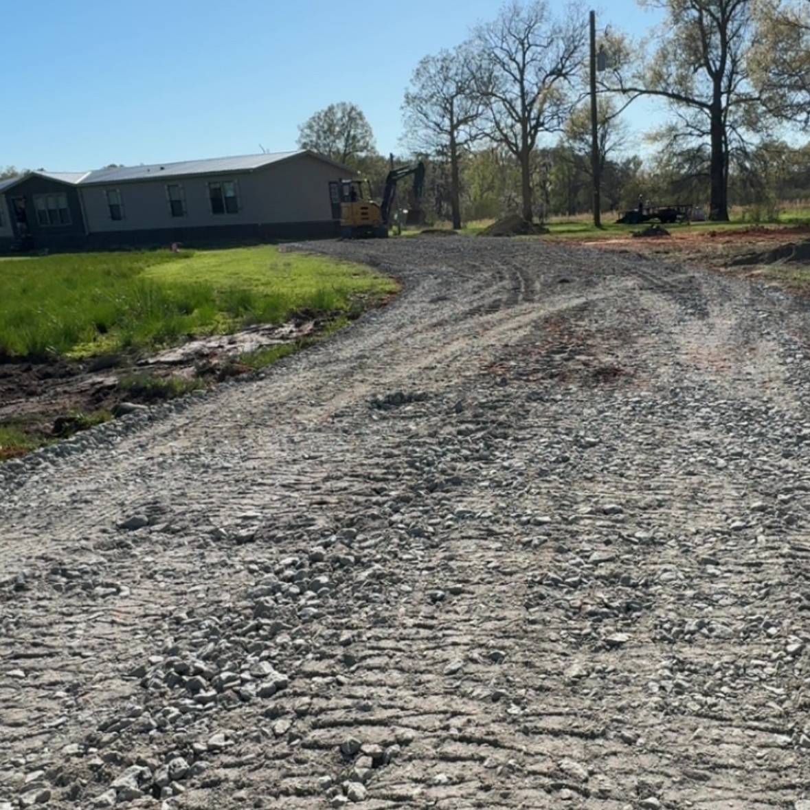 Spreading limestone material across a newly graded driveway path